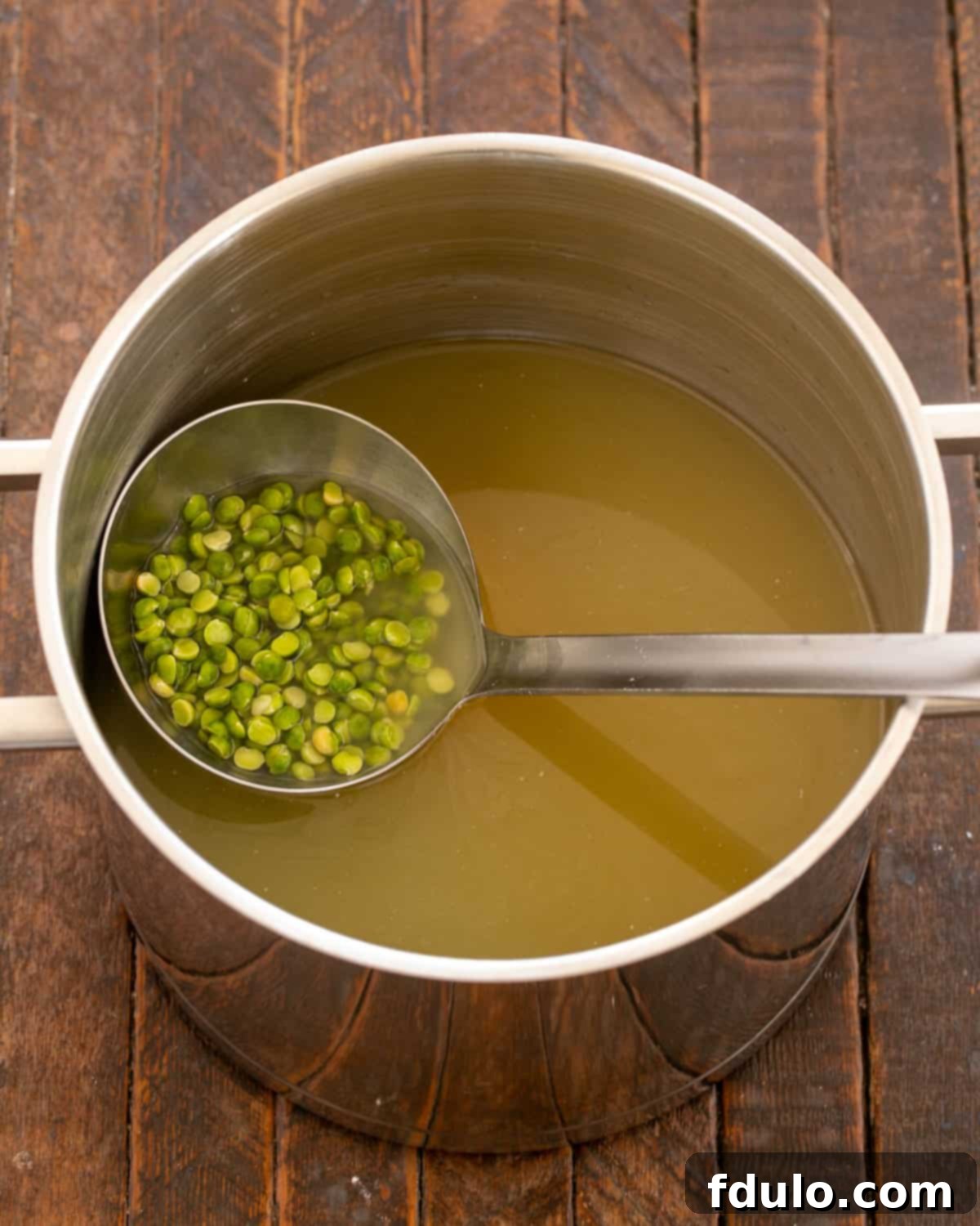 Green split peas simmering in broth in a large pot.