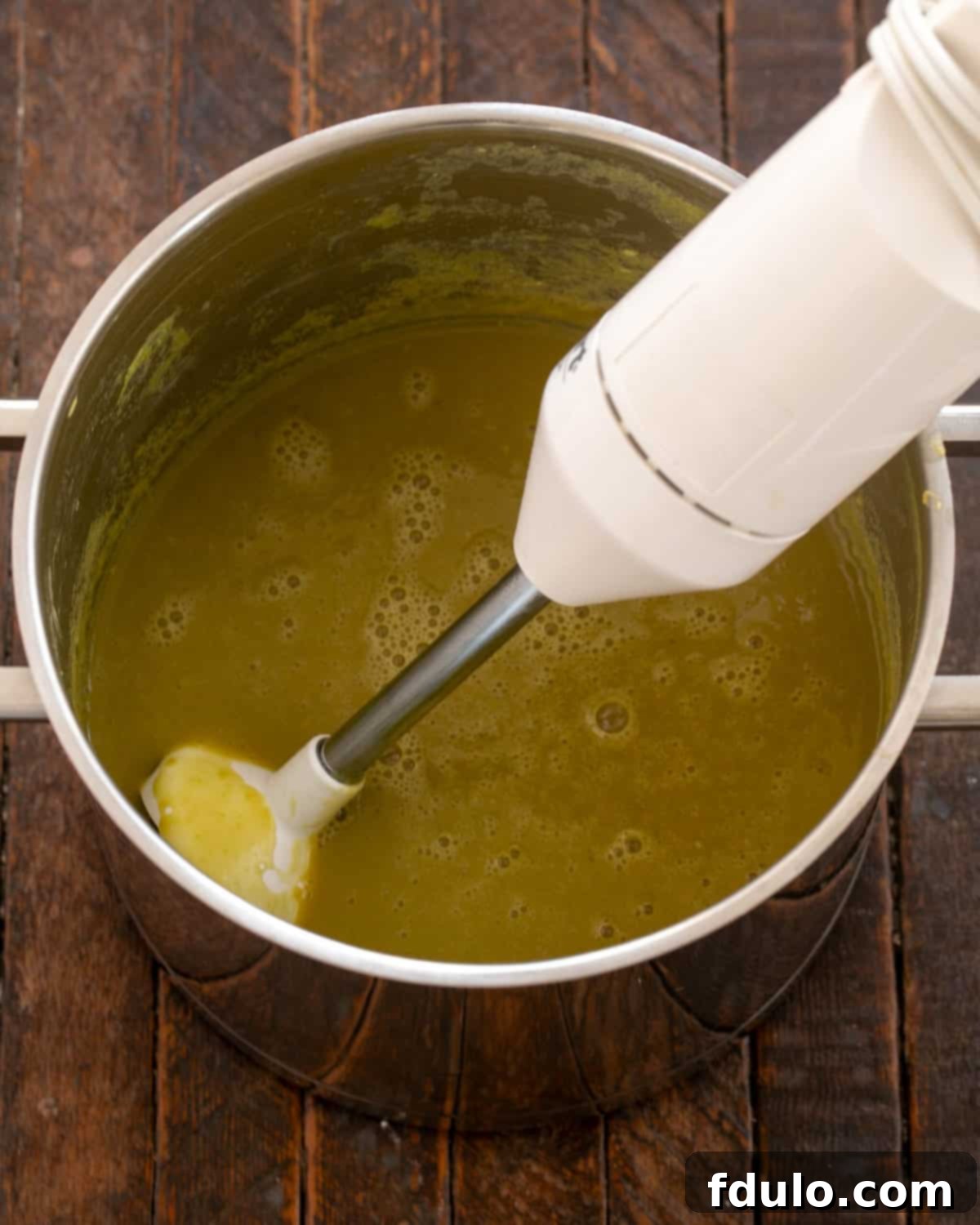 Pureeing cooked split peas in a pot with an immersion blender.