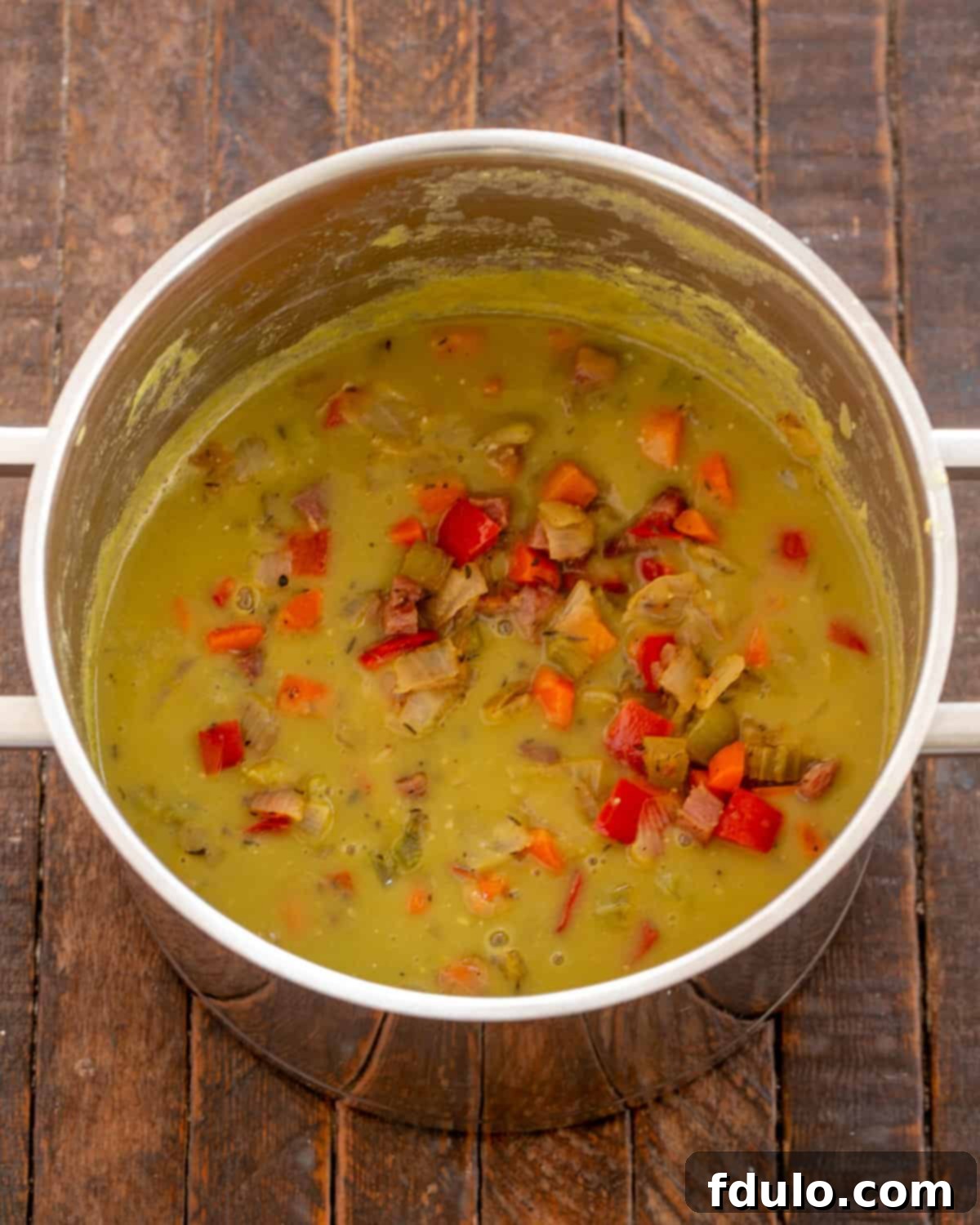Adding sautéed vegetables, diced ham, and a ham bone to the pureed split pea base.