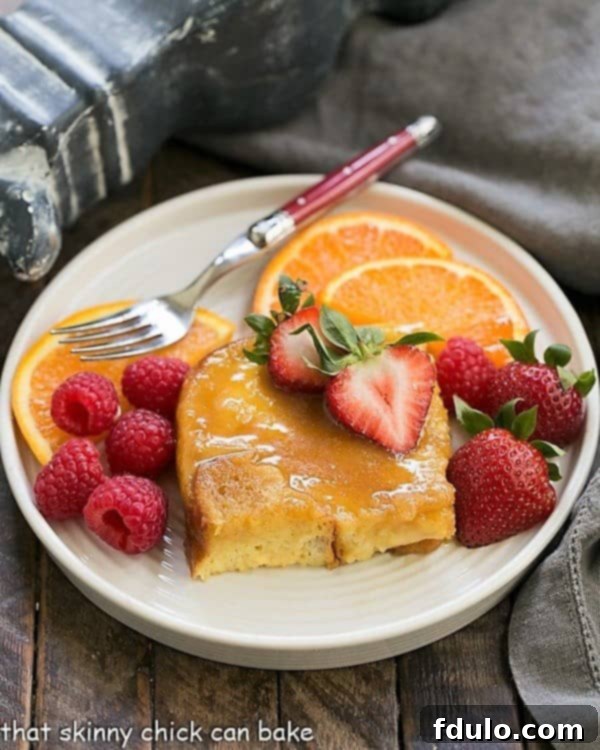 Golden Crème Brûlée French Toast on a round white plate, garnished with fresh berries and a red-handled fork.