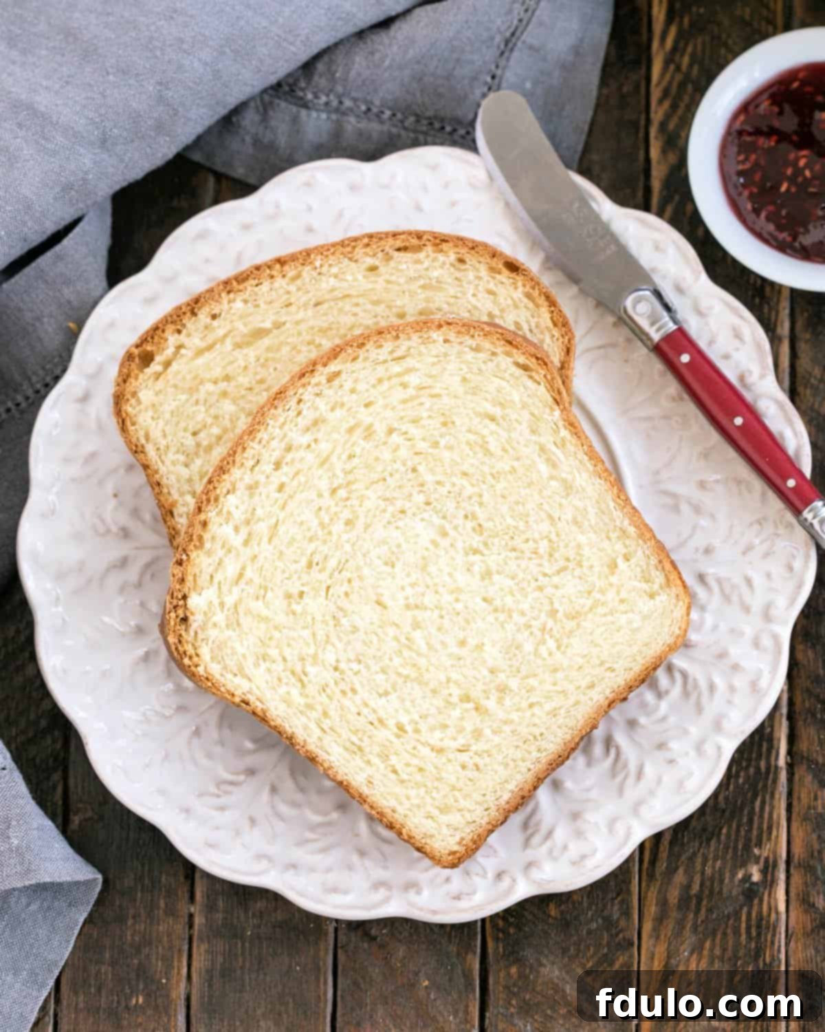 Overhead view of several slices of warm homemade potato bread arranged attractively on a white decorative plate.