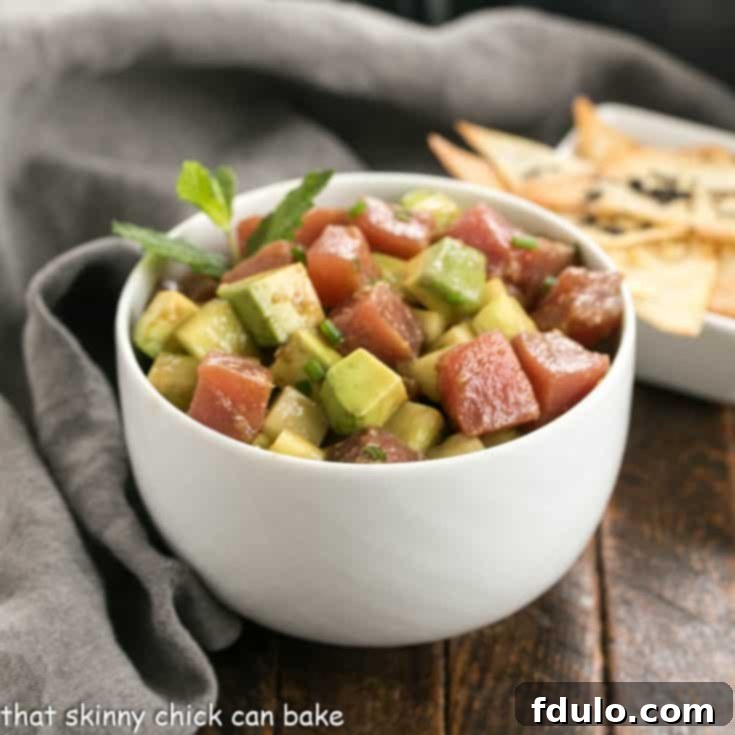 Creamy Avocado Tuna Tartare 4 Tuna tartare with avocados in a white ceramic bowl in front of a small bowl of wonton chips