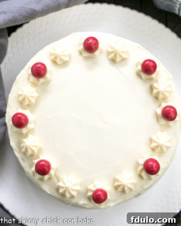 Overhead shot of the Red Velvet Cake, showcasing its vibrant layers and beautifully spread White Chocolate Cream Cheese Frosting on a white cake plate.