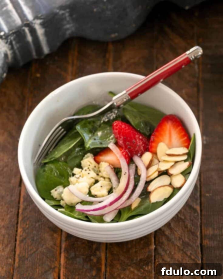 Strawberry Spinach Salad in a small salad bowl with a red handle fork.