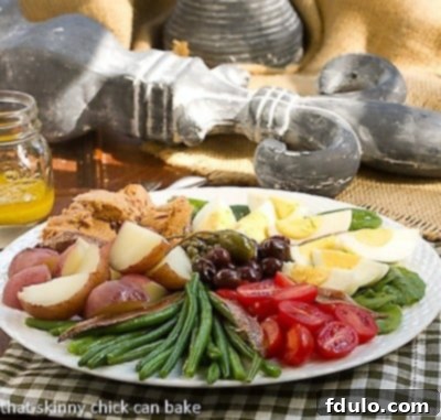 Classic French Salade Niçoise side view on a white plate, showcasing the vibrant arrangement of fresh tuna, vegetables, and dressing.