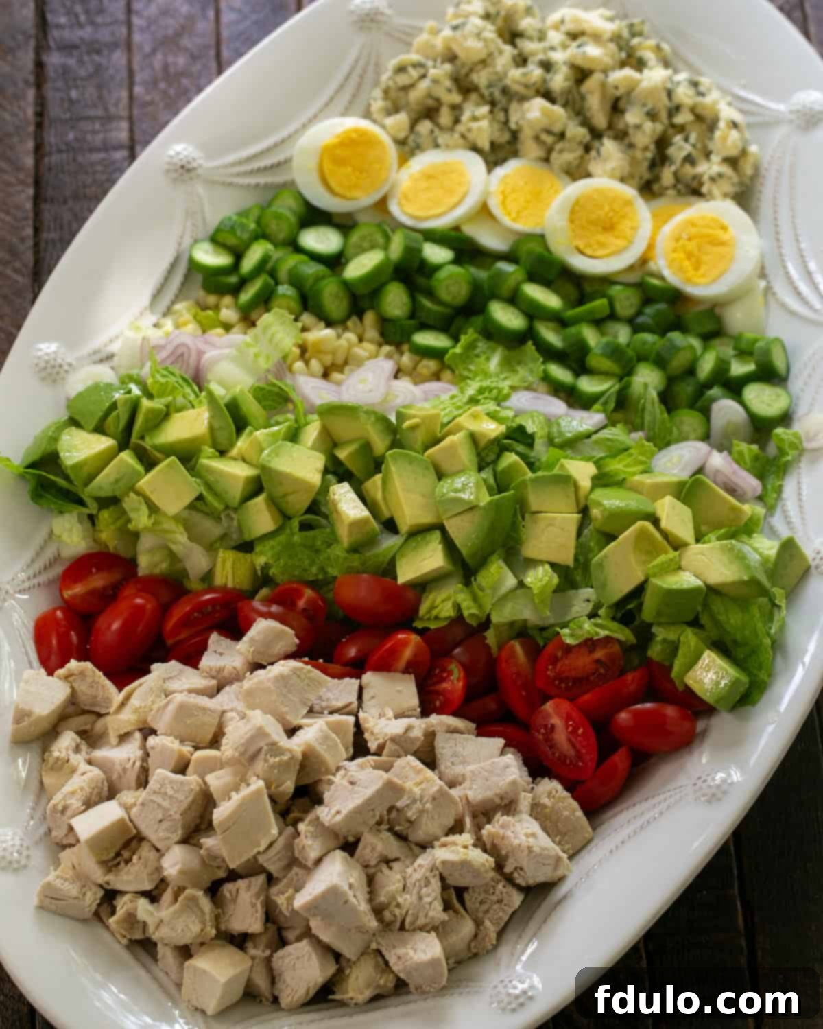Restaurant-Quality Cobb Salad at Home 5 An overhead view of a beautifully composed Cobb salad arranged on a white serving plate, highlighting its colorful sections.