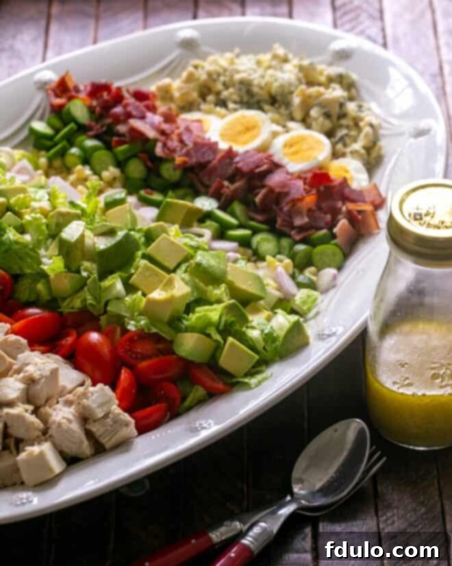 Restaurant-Quality Cobb Salad at Home 6 Cobb Salad ingredients meticulously arranged on a serving platter with dressing nearby, ready to be served.