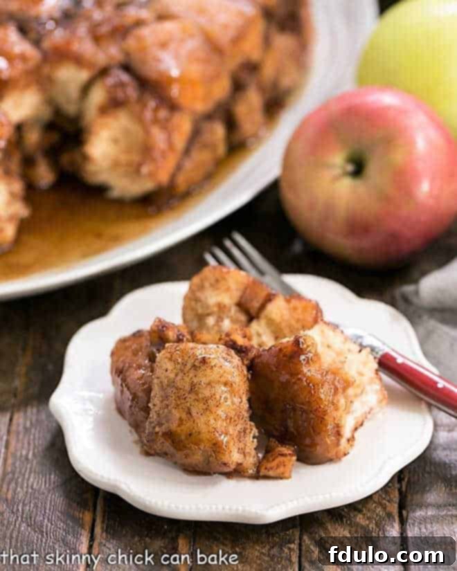 A close-up of Apple Monkey Bread on a white ceramic plate with a red-handled fork, showcasing its gooey texture.