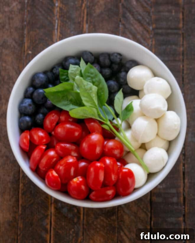 Blueberry Bliss Caprese 4 Caprese salad with blueberries ingredients, including cherry tomatoes, mini mozzarella, and fresh blueberries, placed in a salad bowl.