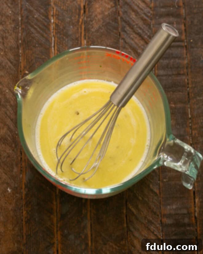 Olive oil and fresh lemon juice being whisked together in a bowl.