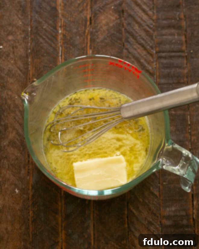 Warm marinade in a saucepan with butter being whisked in.