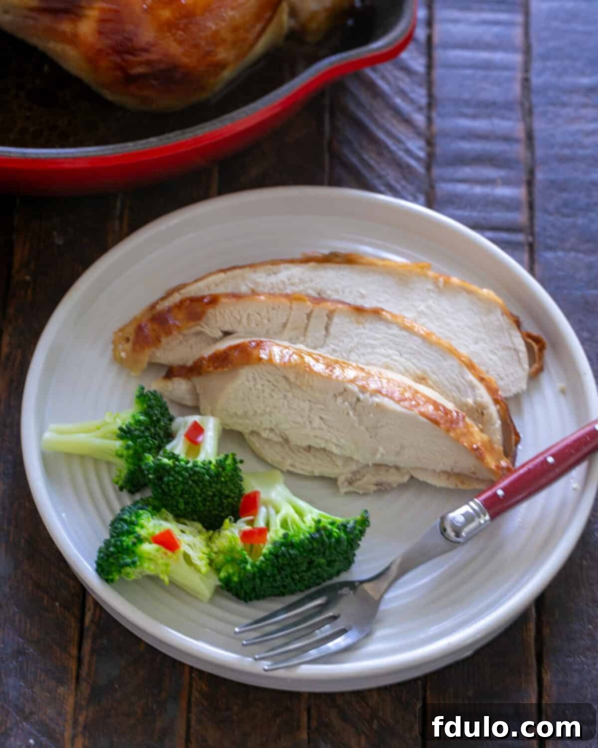 Buttermilk chicken sliced on a plate in front of roasting pan.
