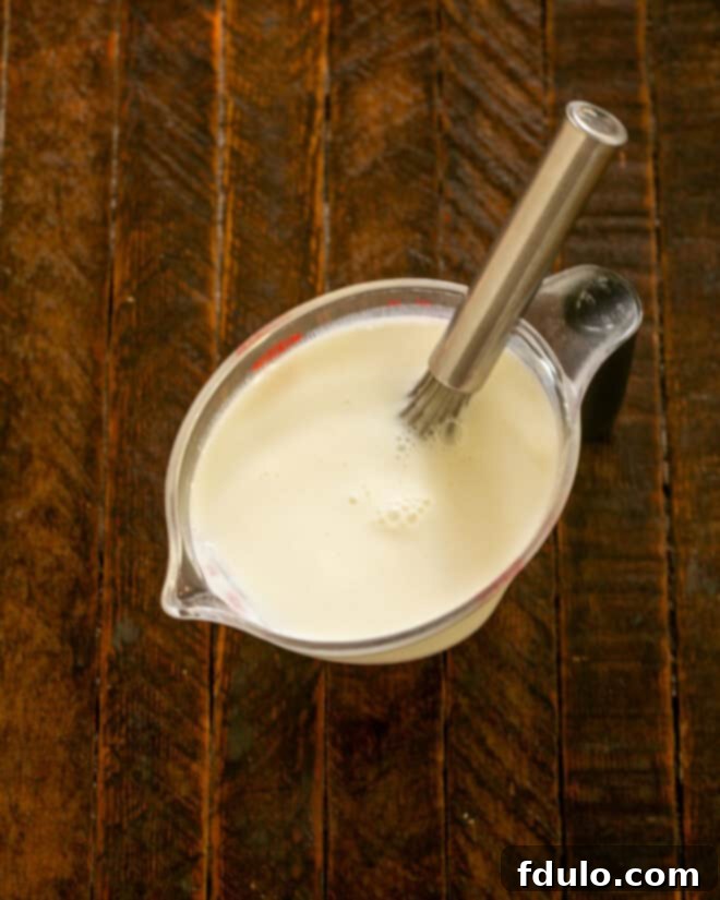 Buttermlk and salt in a measuring cup with a whisk.