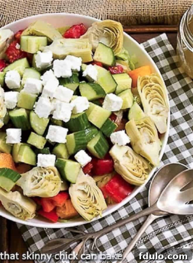 Greek Salad with Feta in a white serving bowl over a green and white checked napkin, showcasing fresh ingredients.