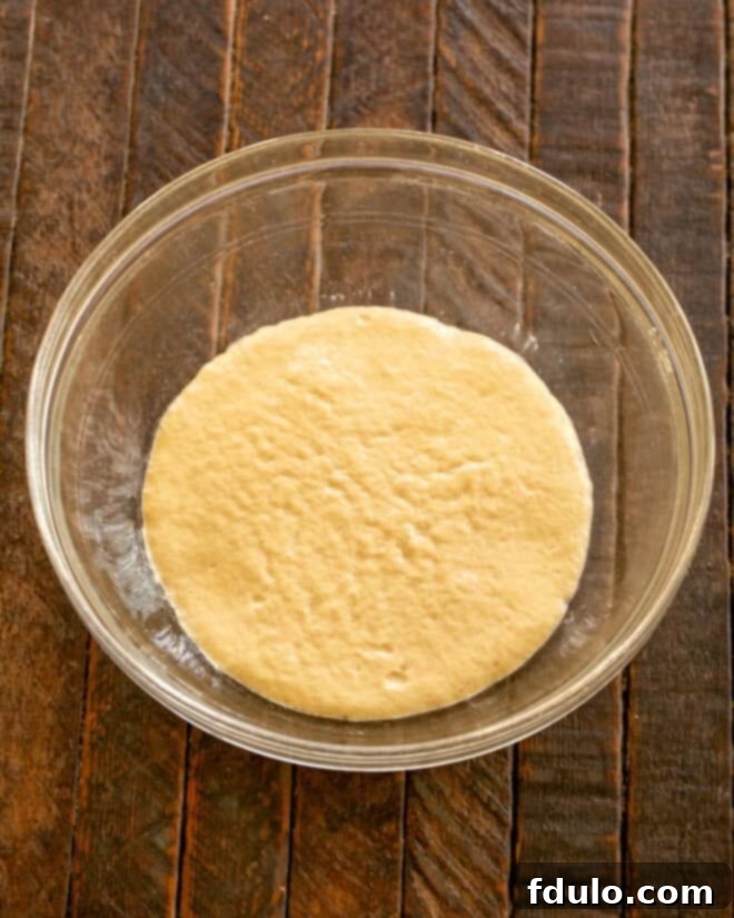 Dry active yeast dissolving in warm water with a teaspoon of sugar, showing the foaming process.