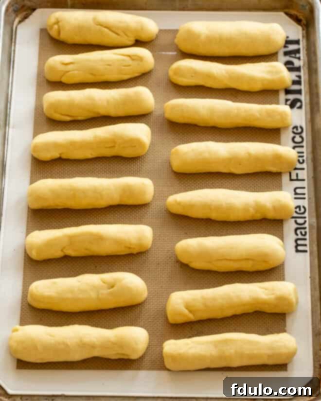 Dough being divided and shaped into long ropes on a floured countertop.