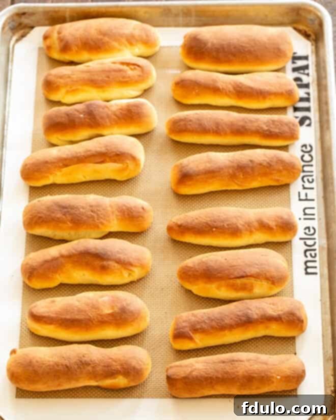 Shaped breadsticks rising on a baking sheet, showing significant volume increase.