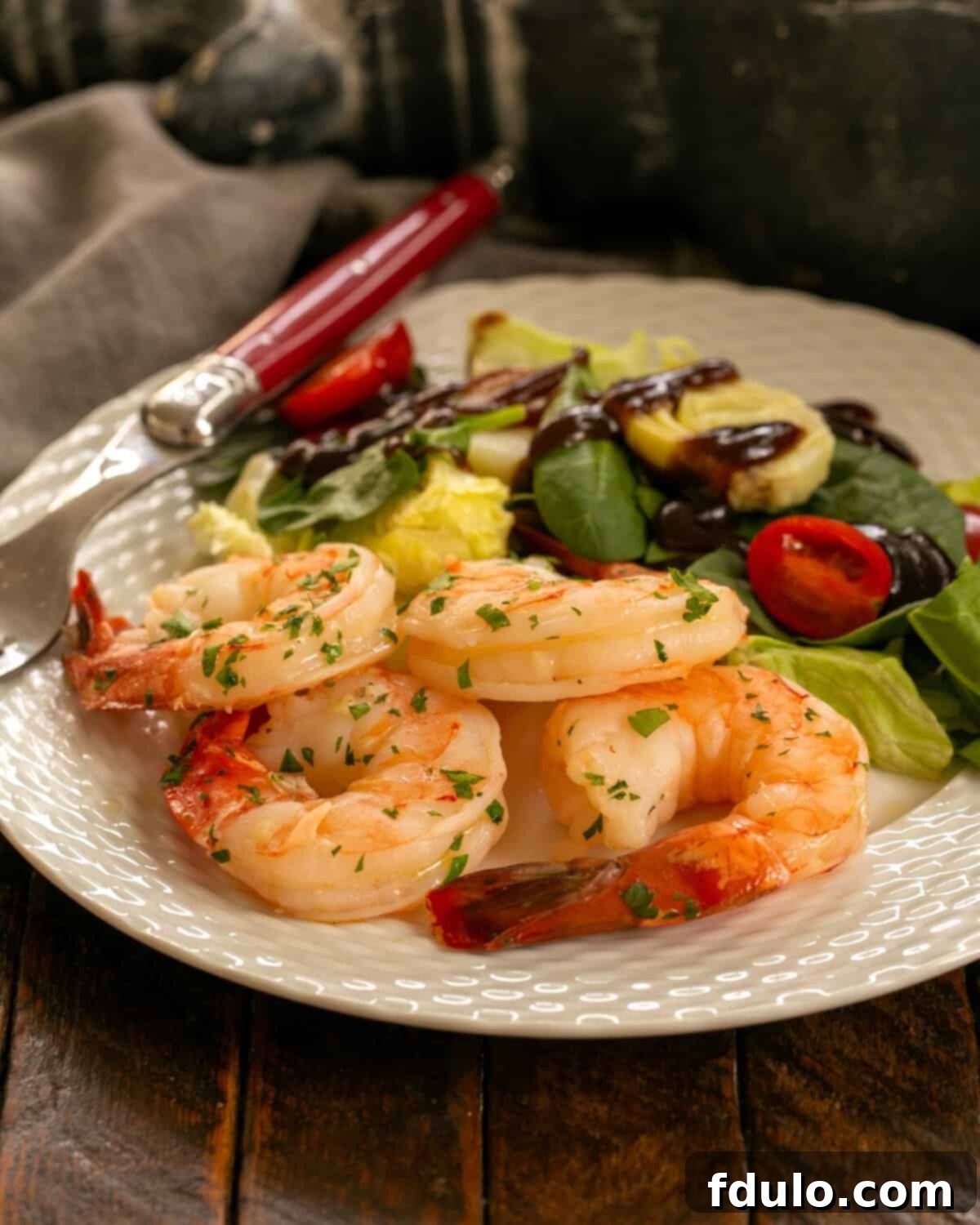 A beautifully plated dish of Shrimp Scampi with a side salad and a red-handled fork, ready to be enjoyed.