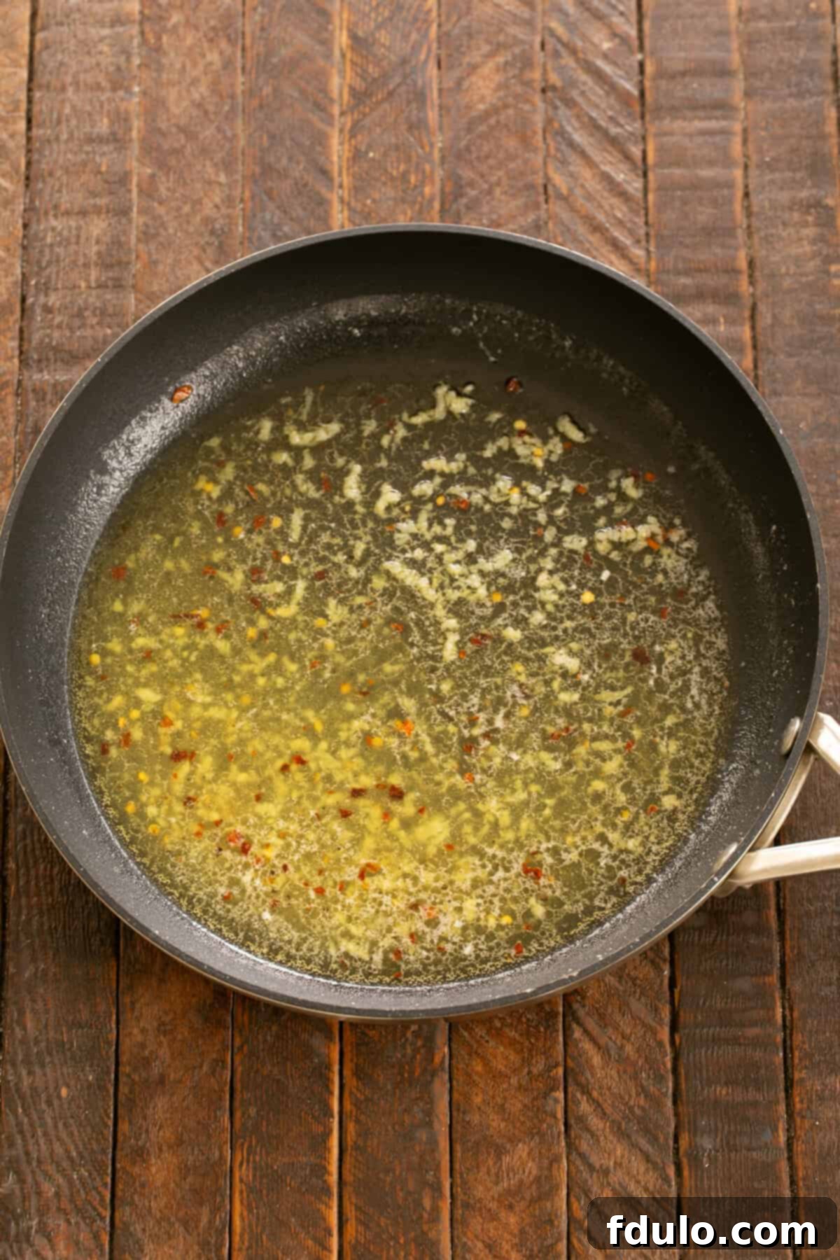 Minced garlic sizzling in the butter and olive oil, releasing its fragrant aroma.