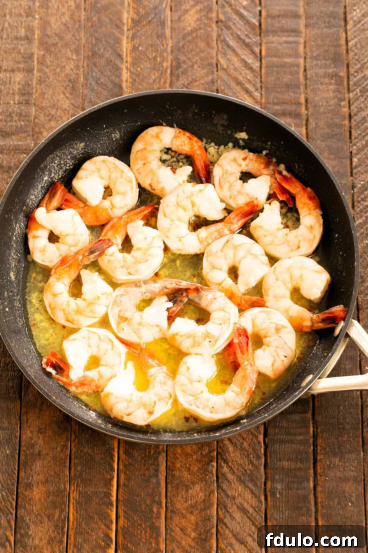 Fresh shrimp being added to the simmering garlic butter sauce, ready to cook to perfection.