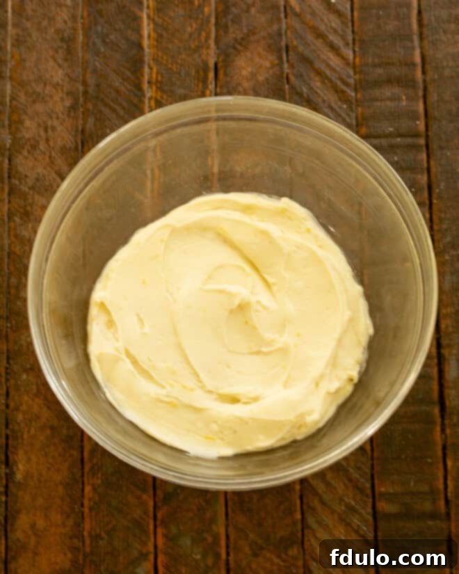 Flaky Croissant French Toast with Fresh Raspberries 4 A bowl containing softened cream cheese, lemon zest, lemon juice, and vanilla extract, being mixed until smooth and creamy. A whisk is in the bowl, and the mixture is ready for the raspberries.