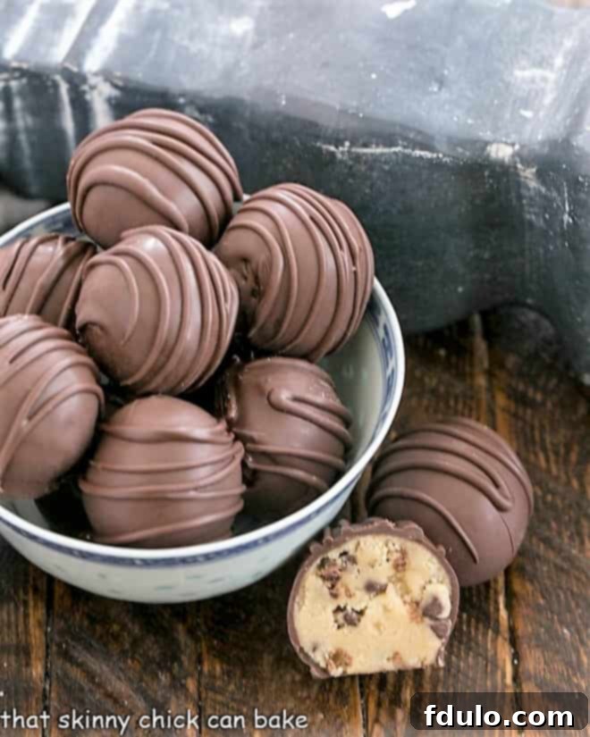 A delightful bowl of Cookie Dough Bites, with one whole and one perfectly cut-open truffle showcasing the rich filling on the side