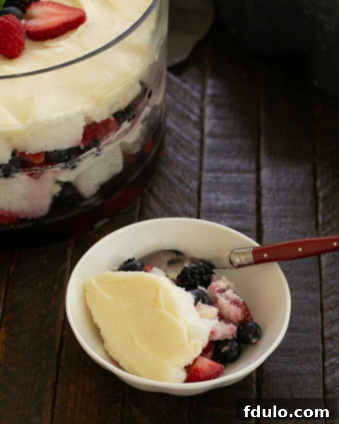 Small bowl of berry trifle with a spoon off to the side of the serving bowl.