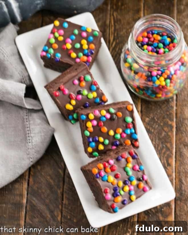 An overhead shot showcasing a tray of perfectly sliced homemade cosmic brownies, adorned with vibrant sprinkles and a rich, dark ganache.