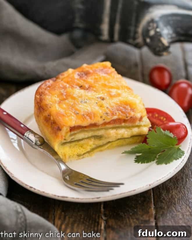 Low Carb Chili Relleno Casserole - Layers of gooey cheese, eggs, tomatoes, and mild peppers create an irresistible Tex-Mex dish! A single slice of Low Carb Chili Relleno Casserole on a round white plate, accompanied by a red-handled fork, inviting a bite of its cheesy, eggy goodness.