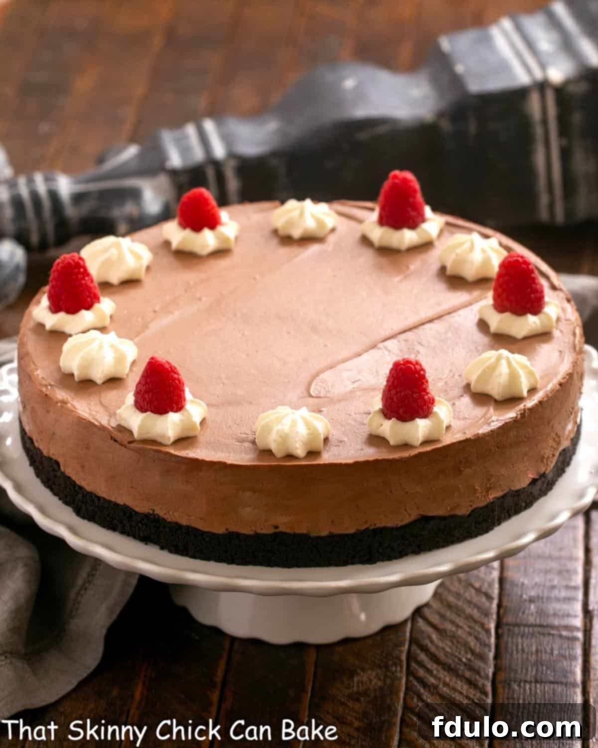 A beautifully set Chocolate Mousse Cake on a pristine white ceramic cake stand, ready to be sliced and served.