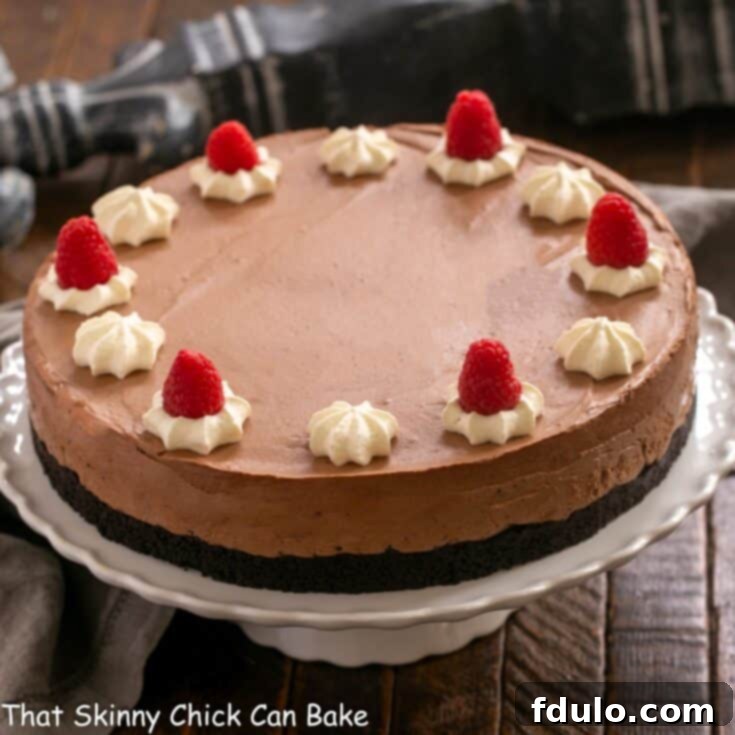 A beautifully presented Chocolate Mousse Cake on a white cake stand, showcasing its smooth top and elegant appearance.