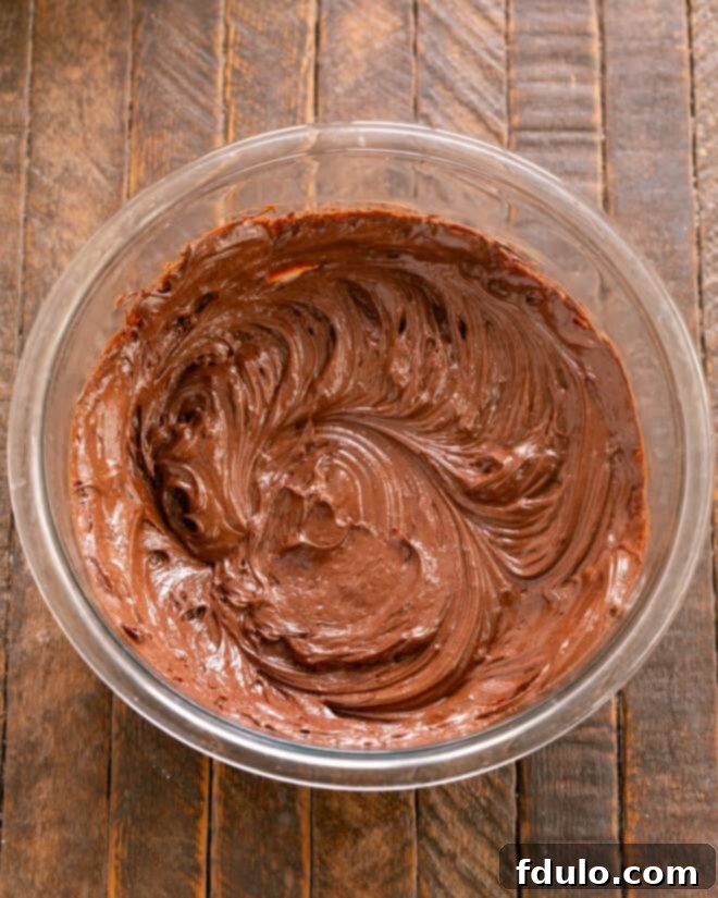 Step-by-step image showing melted chocolate being mixed with whole eggs in a bowl until thoroughly combined and smooth.