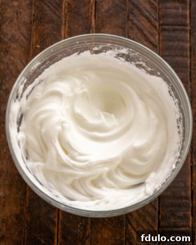 Step-by-step image showing egg whites being whipped in a clean bowl, demonstrating the stiff peaks that should be achieved.