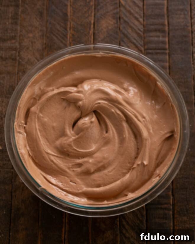 Step-by-step image showing whipped egg whites being gently folded into the chocolate mixture, illustrating the technique to maintain airiness.