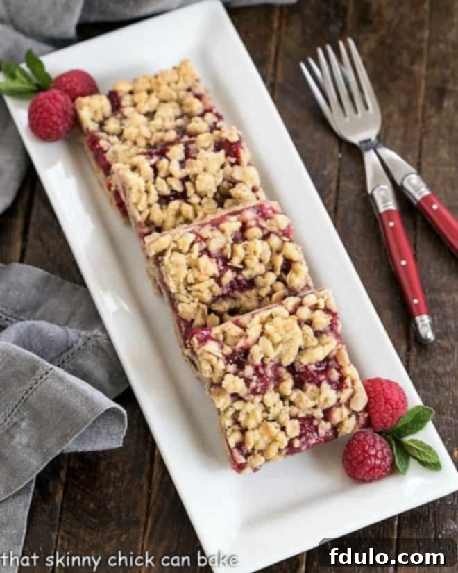 Overhead view of perfectly baked raspberry oatmeal bars with a golden streusel topping, arranged on a white serving tray, ready to be enjoyed.