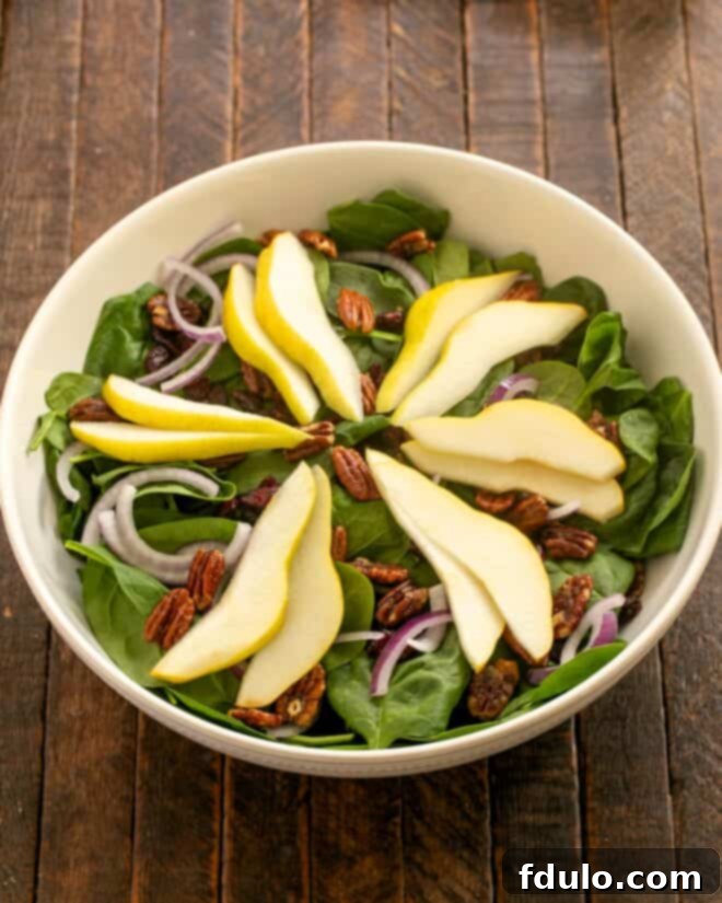 Overhead view of Spinach and Pear Salad in a serving bowl.