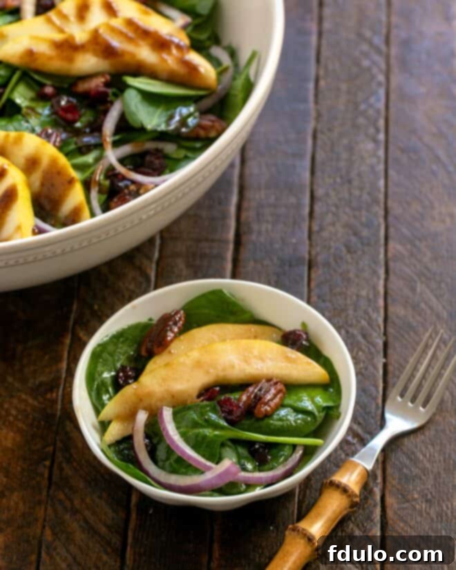 Serving of spinach and pear salad with a bamboo handled fork.