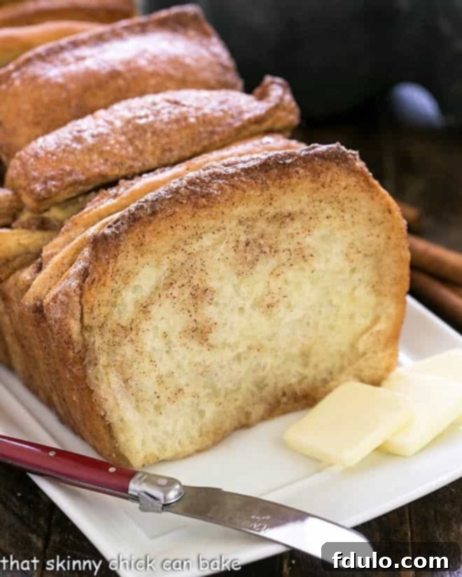 Warm Cinnamon Pull-Apart Bread on a white serving tray with a silver knife and butter pats, ready to be enjoyed.