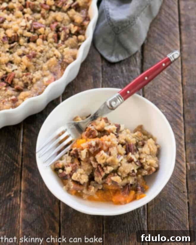 A warm serving of Praline Topped Sweet Potato Casserole in a white bowl, ready to be enjoyed.