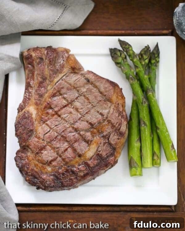 Perfectly grilled rib eye steak served on a dinner plate with fresh asparagus.