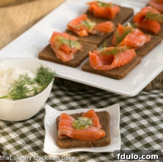 Dilled Gravlax with Mustard Sauce beautifully plated on cocktail rye bread, garnished with fresh dill.