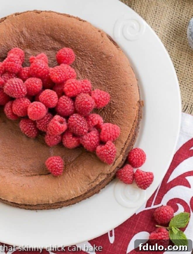 Overhead view of Chocolate Mousse Torte on white ceramic serving plate topped with fresh raspberries, elegantly presented