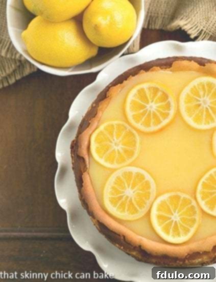 Overhead view of a beautifully prepared Lemon Bar Cheesecake, showcasing its vibrant yellow top with lemon curd and candied lemon slices.