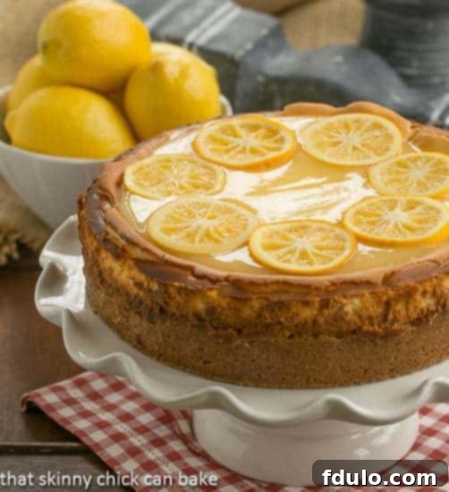 Lemon Bar Cheesecake elegantly presented on a white cake stand, highlighting its smooth texture and decorative candied lemons.