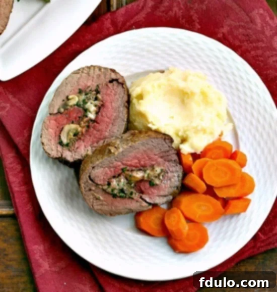 Decadent Gorgonzola Mushroom Stuffed Beef Tenderloin 2 Slices of Gorgonzola and Mushroom Stuffed Beef Tenderloin on a dinner plate showcasing the savory filling