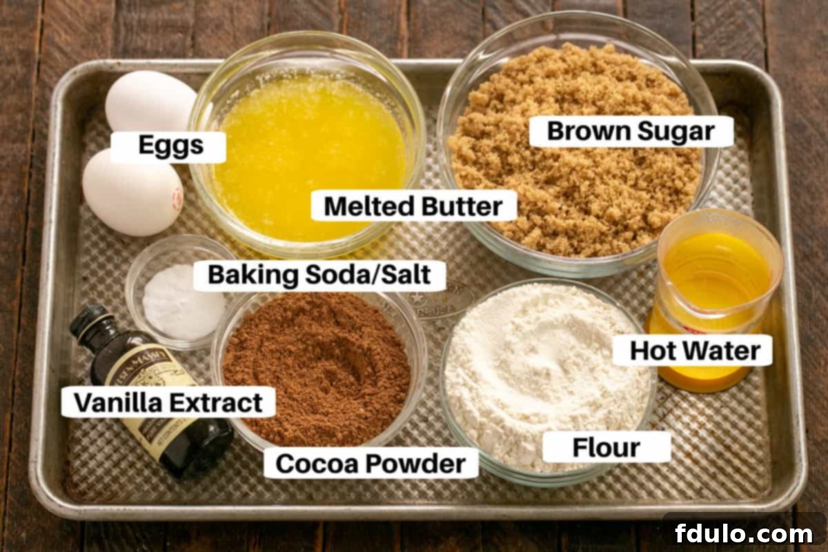 Carefully arranged ingredients for the fudge cake on a white sheet pan, clearly labeled and ready for baking.