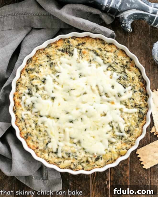 Overhead view of Hot Spinach and Artichoke Dip in a round white dish, garnished and ready to be enjoyed.