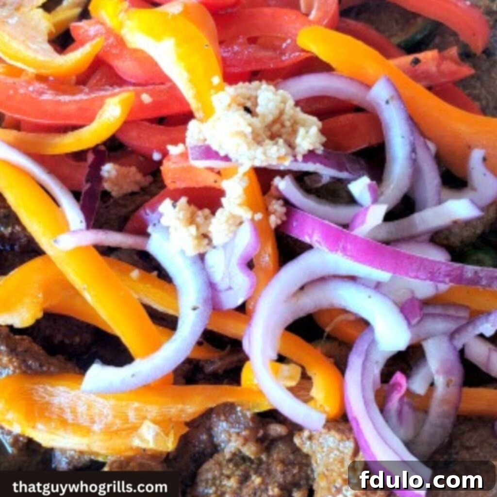 Sizzling steak fajitas with colorful peppers and red onion cooking on a Blackstone griddle, a vibrant and delicious meal preparation.