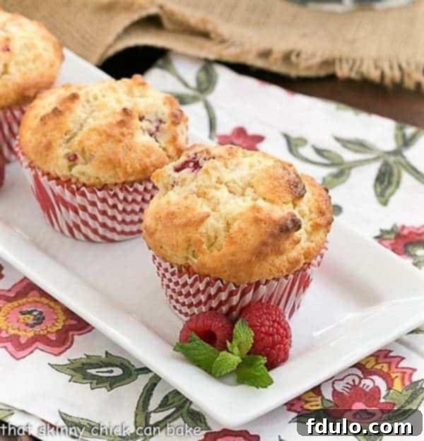 Spectacular Raspberry White Chocolate Muffins - sweet, tender and full of fresh berries and white chocolate Spectacular Raspberry White Chocolate Muffins on a white rectangular platter, freshly baked and ready to enjoy.