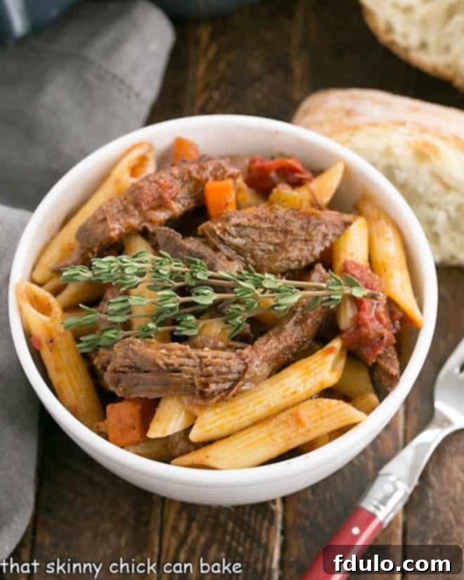 A white bowl filled with penne pasta generously coated in rich beef ragu, accompanied by a slice of crusty bread and a fork, inviting a delicious meal.
